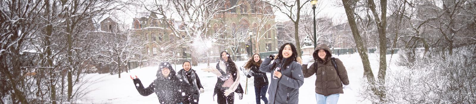 Students on campus playing in the snow.
